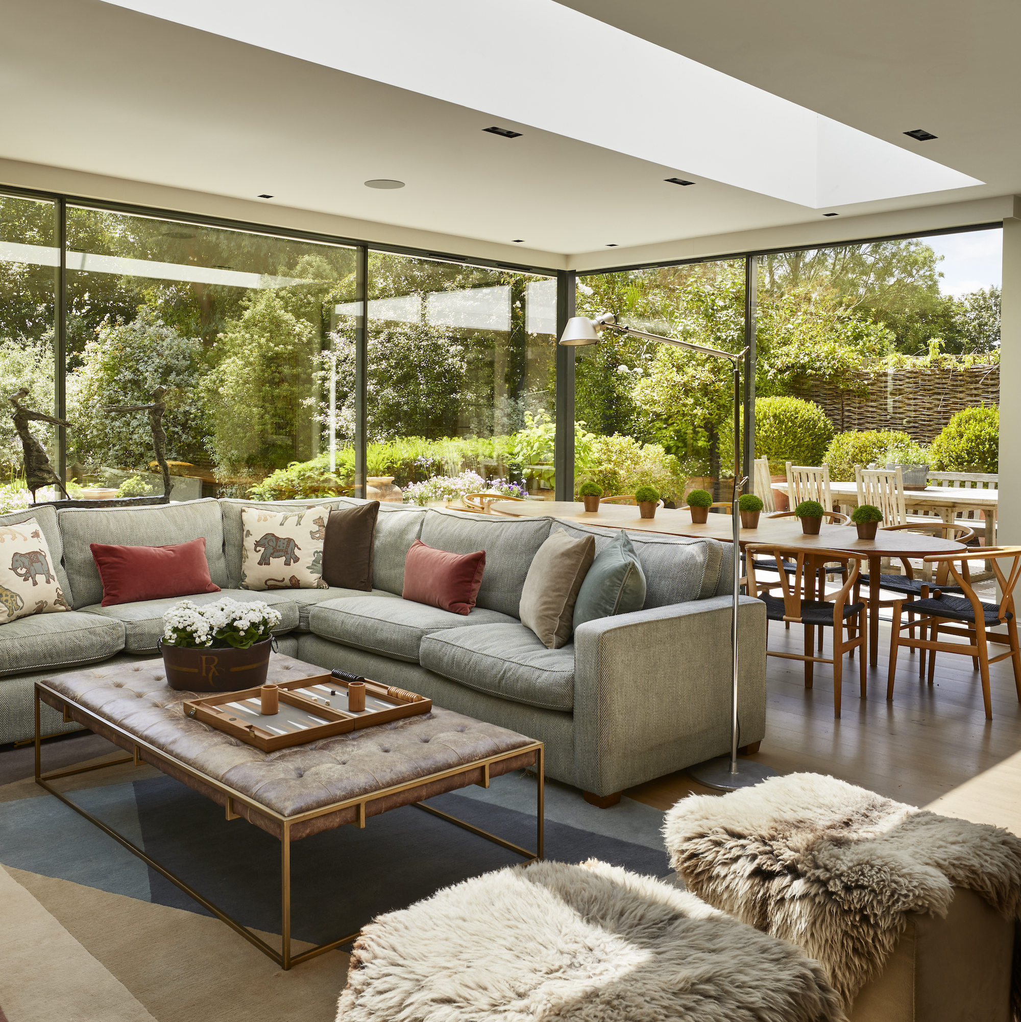 open plan contemporary living space with glazing and corner sofa with dining table behind