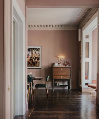 earthy pink and brown dining room with wooden floors and vintage furniture