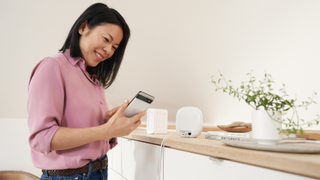 A woman using a Pixel smartphone next to the Nest Wifi Pro