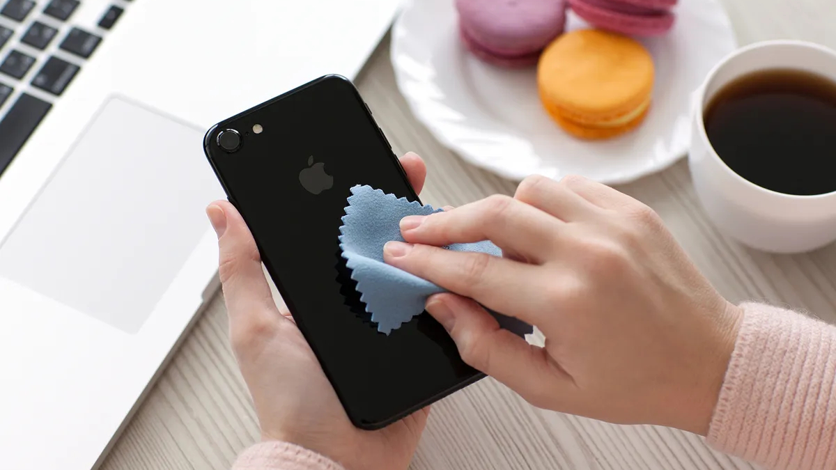 Person cleaning an iPhone with a cloth