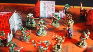 An array of Space Marine and Plague Marine models on an orange battlemat littered with MDF ruins