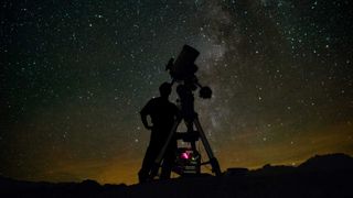 Astronomer using telescope to observe the night sky