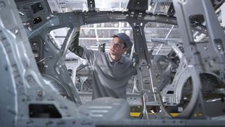 Worker in a car factory inspecting the exterior shell of a car