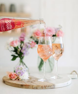 two wine glasses filled with sparking drink and pink flowers bottlegreen