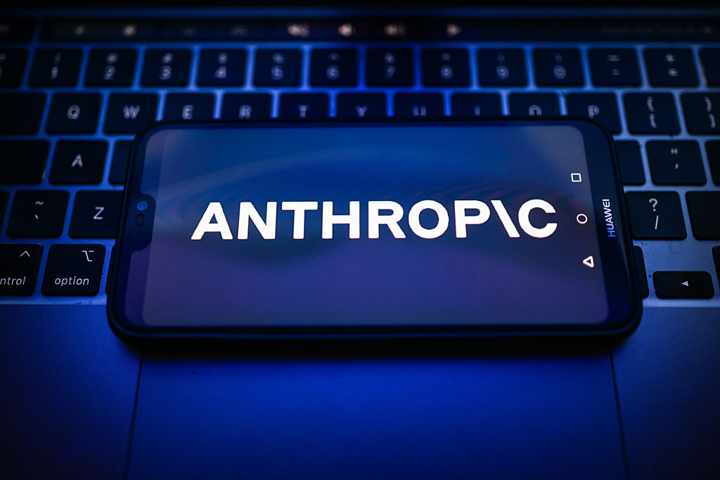 Anthropic logo is displayed on a smartphone on the top of a laptop.