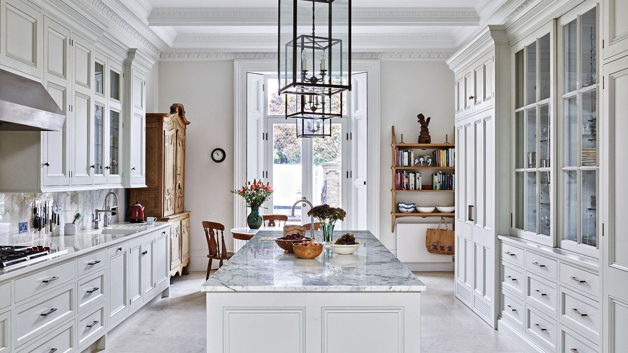 All white kitchen with kitchen island along the centre and metal frame rectangular lantern ceiling lights