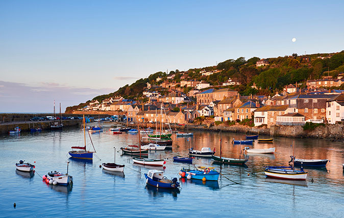 The first light of dawn catching the cottages along the waterfront, overlooking the picturesque Cornish harbour of Mousehole.