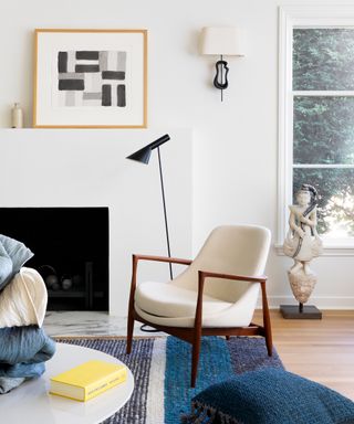 Small living room lighting ideas with white walls, white and wood mid-century modern armchair, blue rug and black floor reading lamp