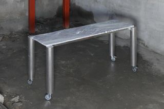 Narrow work table with wheels, featuring metal legs and marble top