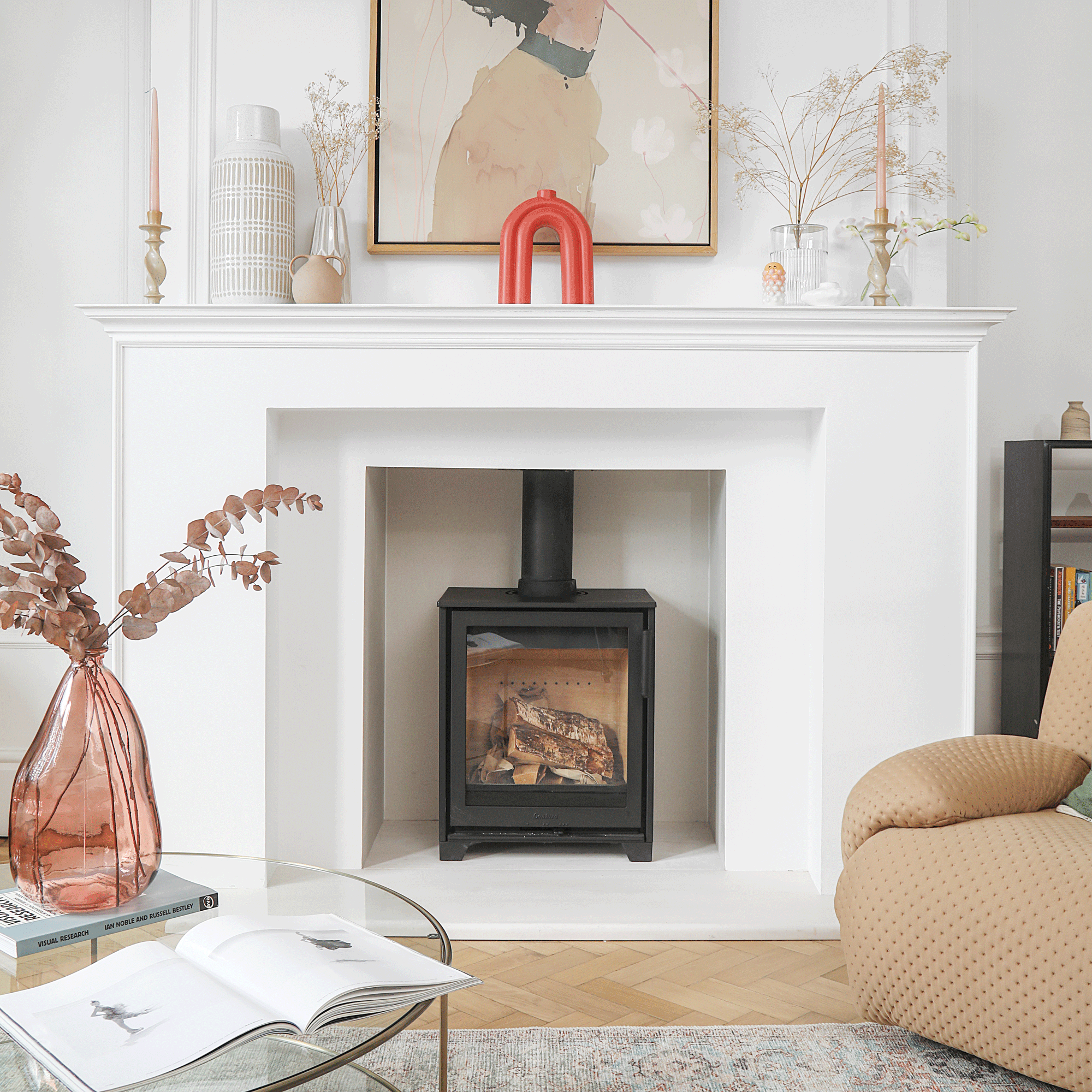 a living room with a large white fireplace and a compact woodburner