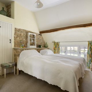 bedroom with twin beds and beige carpet and stone wall