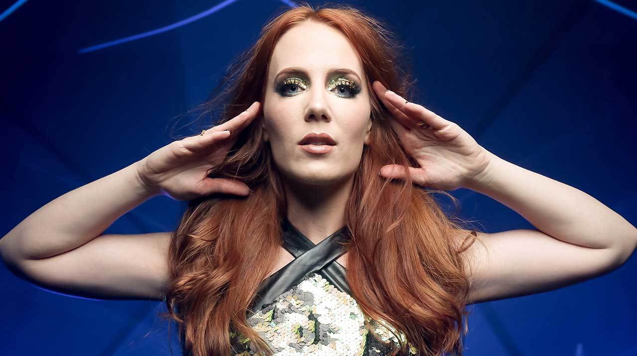 Epica’s Simone Simons with her hands touching the sides of her head