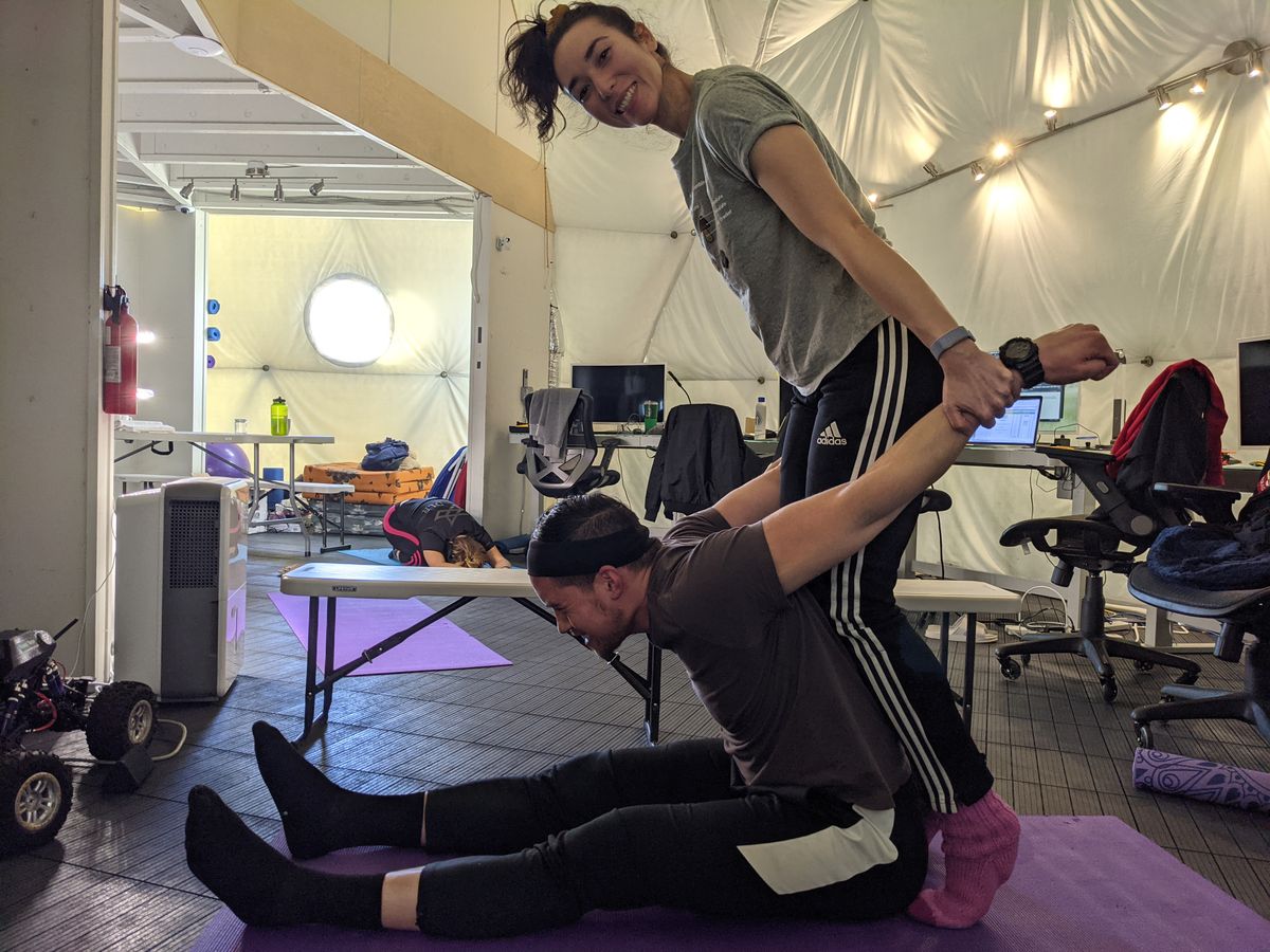 Valoria 2 crewmembers doing rigorous stretching post-handstand training at the HI-SEAS research station during a simulated Mars mission.