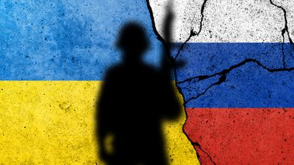 Shadow of soldier in front of flag of Ukraine and Russia painted on a brick wall