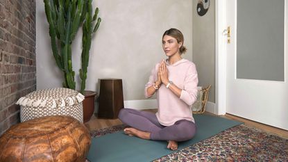 person meditating on a mat in their spare room