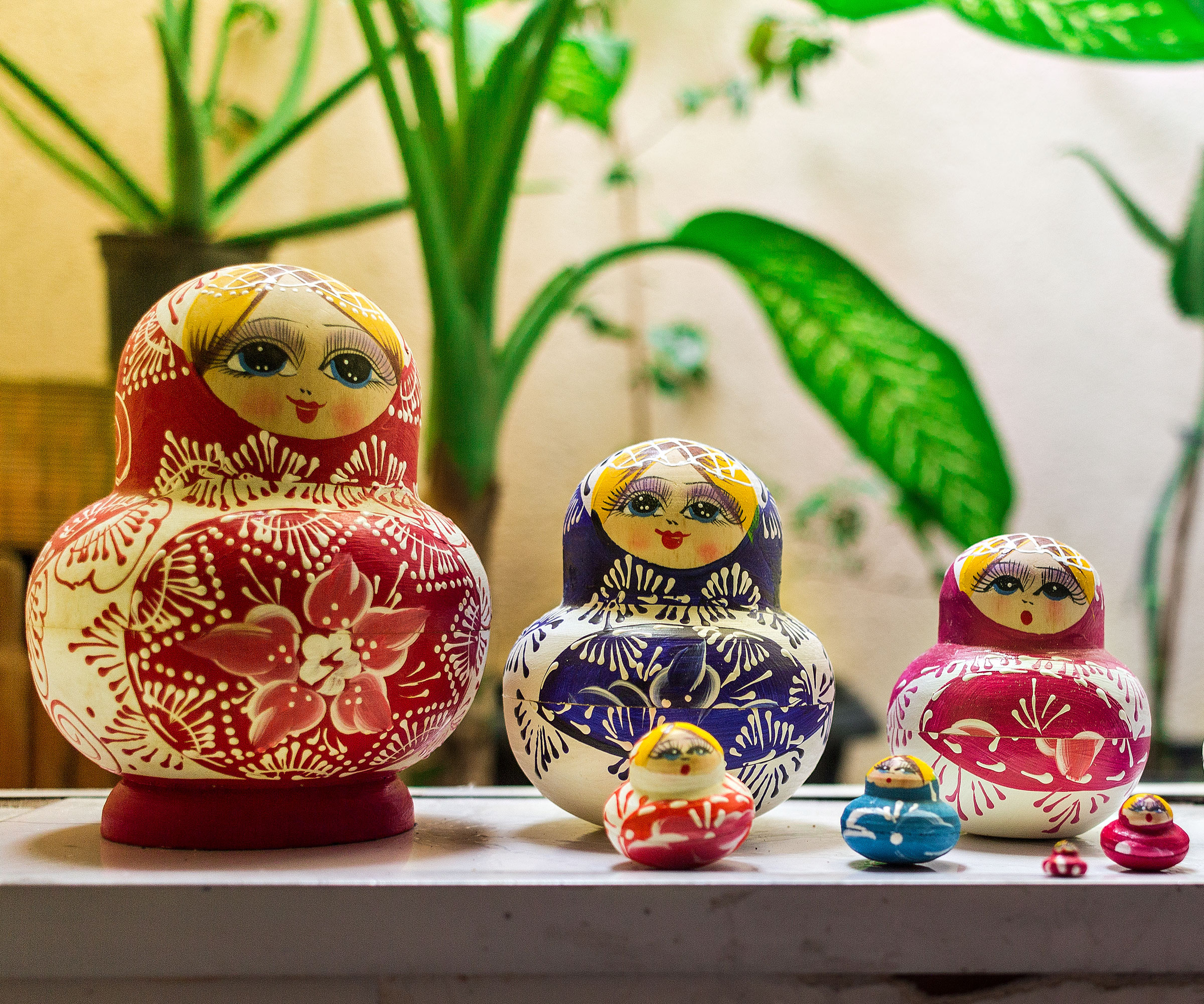 Russian dolls on work surface with houseplants in background