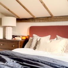 Bed under eaves ceiling with wooden beams