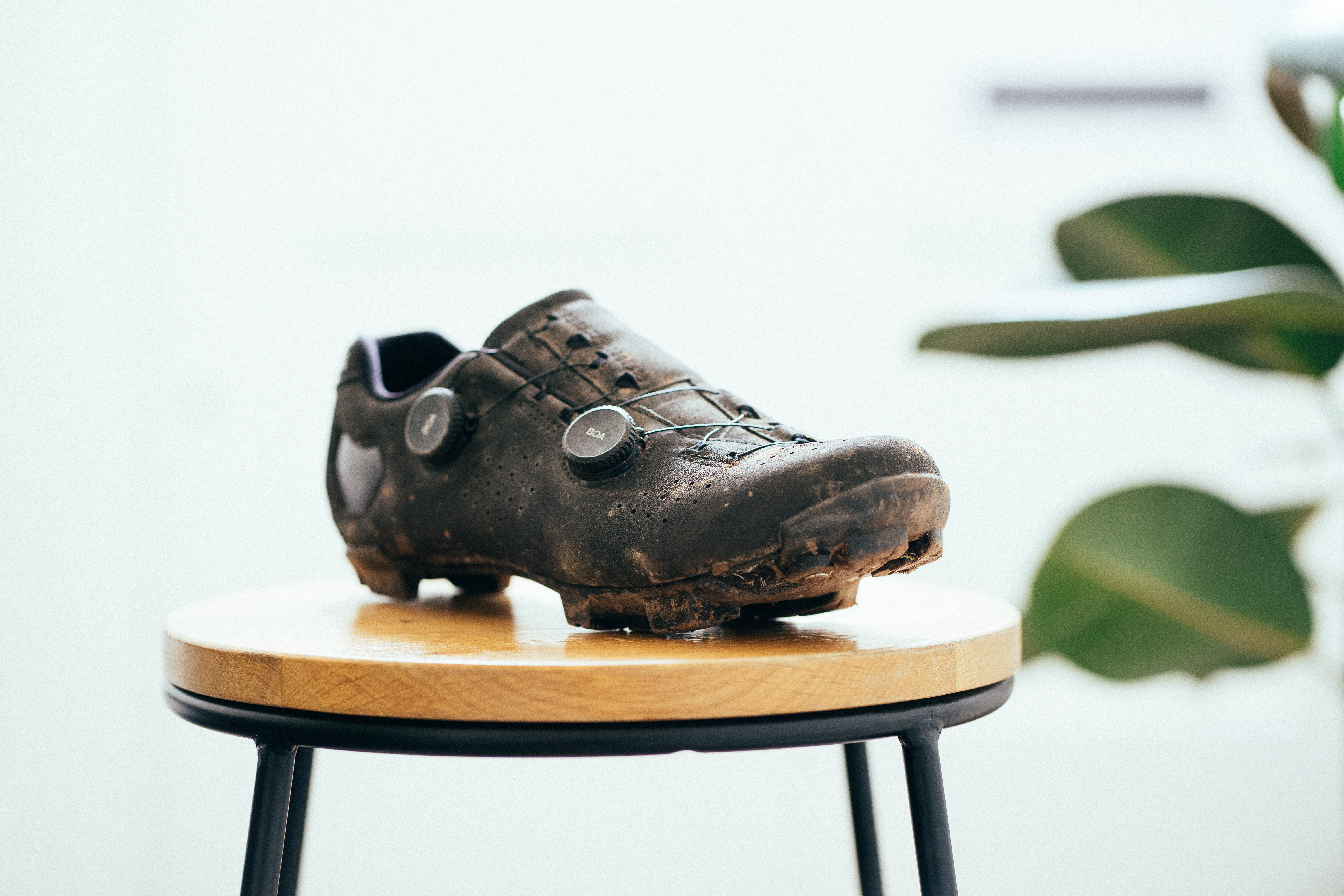 A black gravel shoe on a wooden stool against a white background