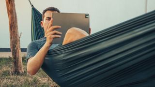 Man sitting in hammock using laptop