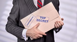 A man in a suit holding confidential documents