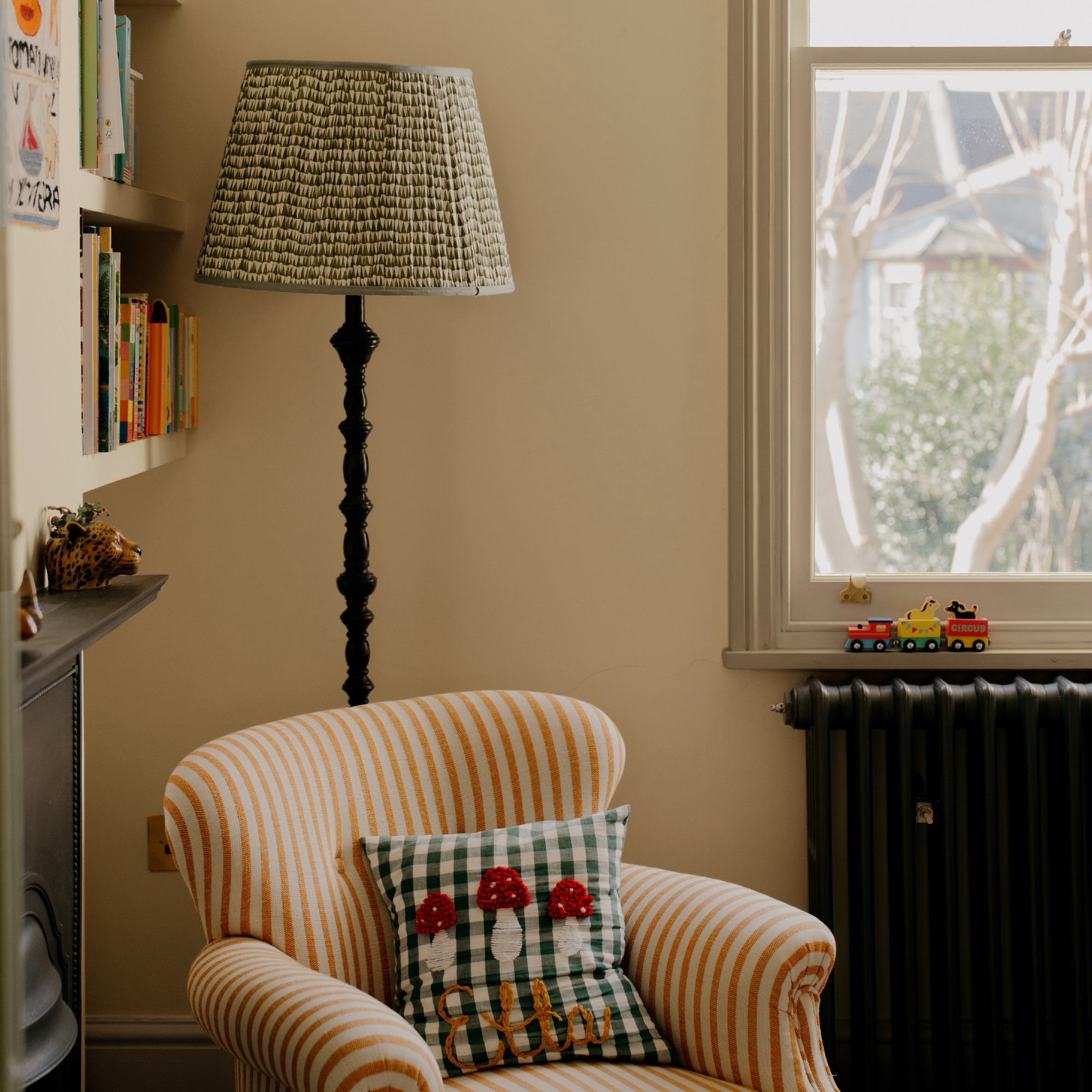 A living room painted in COAT's Cheap Souffle and Camber styled with a striped armchair and a patterned floor lamp