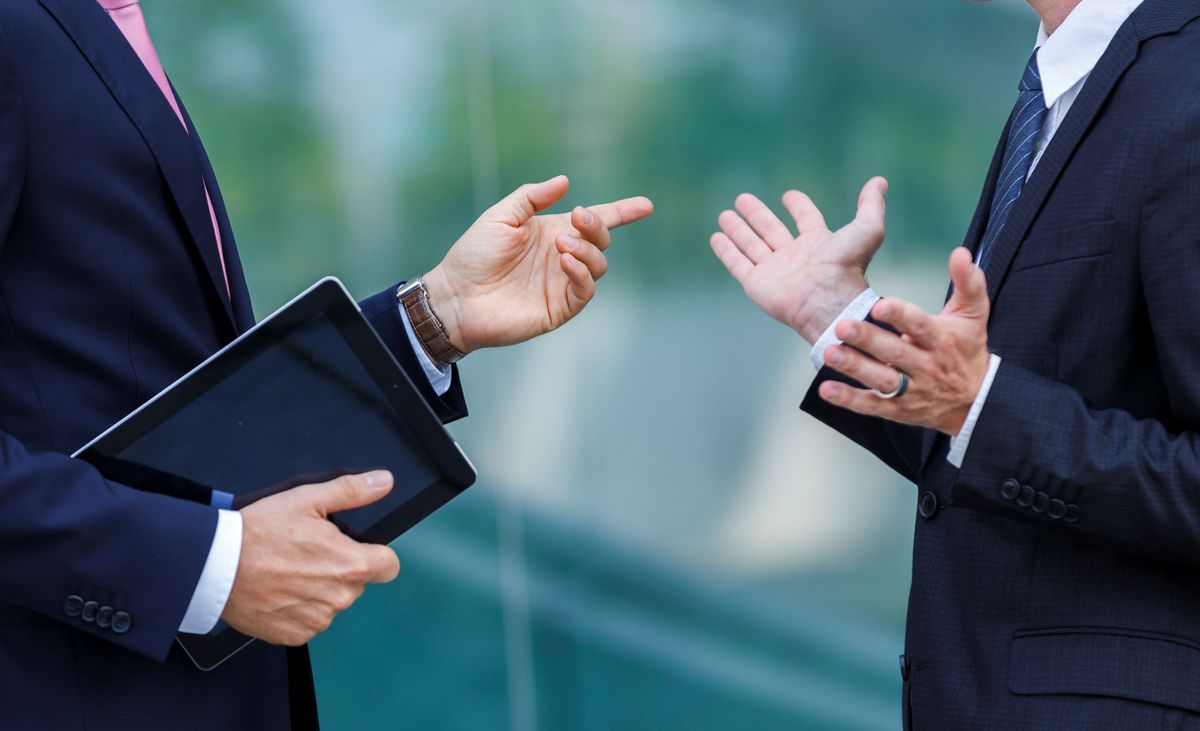 Two men in business suits have a discussion