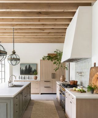 light and airy kitchen with white walls, wooden cabinets, exposed wooden ceiling beams