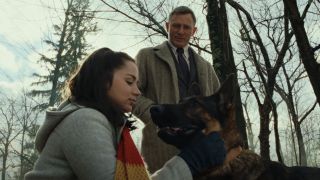 Ana de Armas petting a dog and Daniel Craig standing above them.