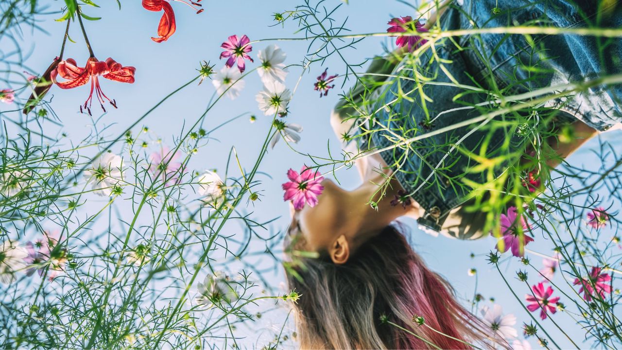 A woman holding her head up in a bed of flowers