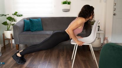 A woman performing a push-up with her hands elevated on a chair