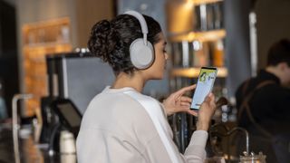 Woman wearing Sony WH-1000XM5 while using her phone