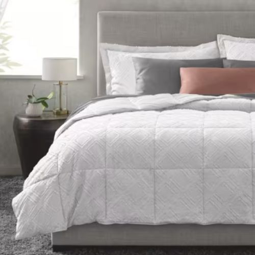 Lifestyle image of gray bed with duvet, pillows and wooden side table