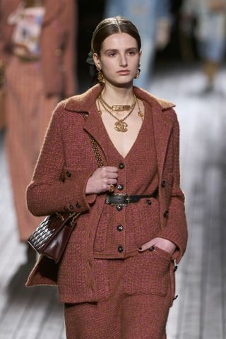 Woman in bouclé cardigan on the Chanel runway.