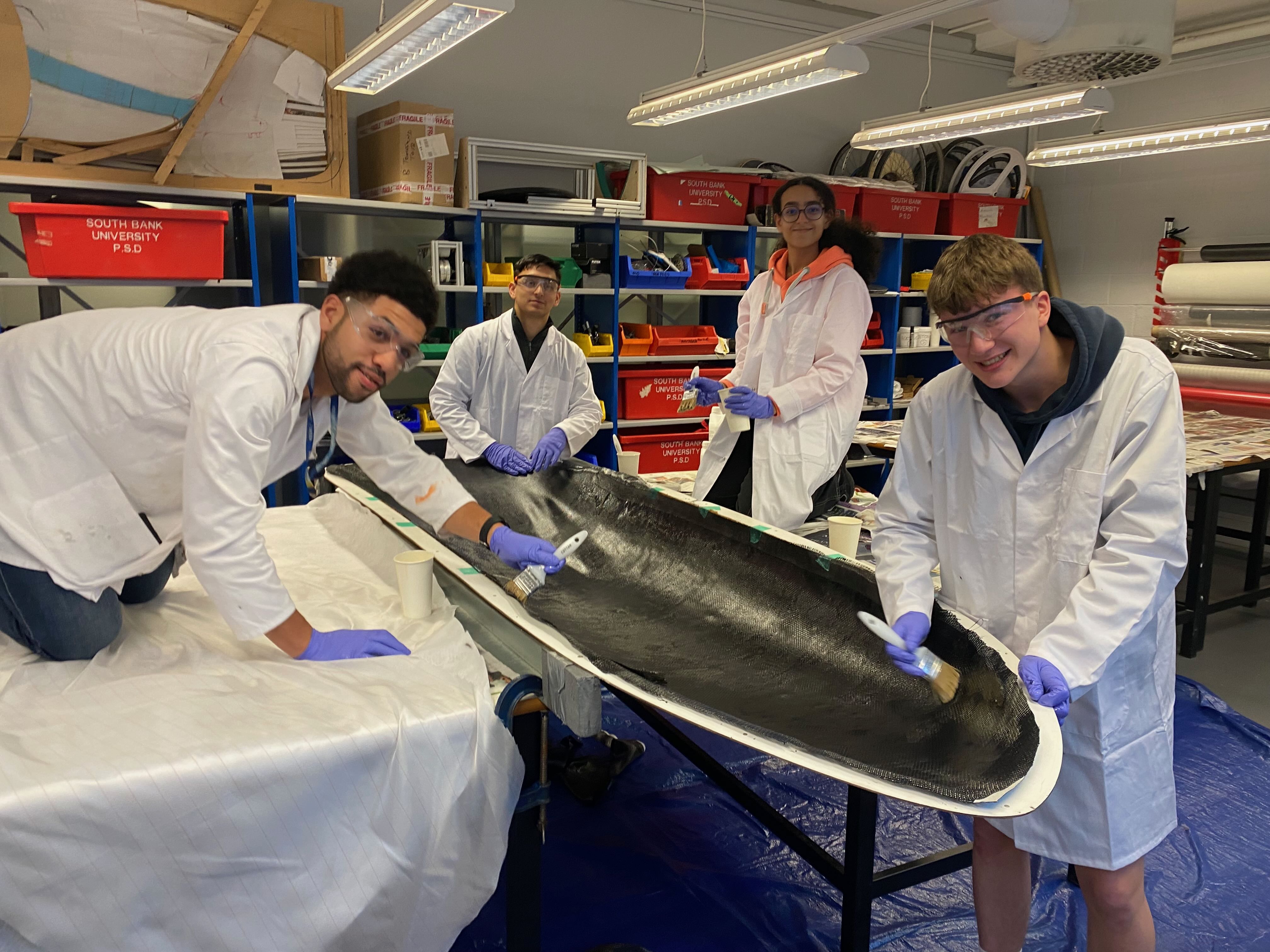 Students gather round a half-shell of an aerodynamic bike cover