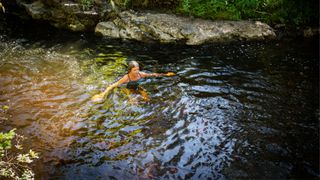 Woman wild swimming with rocks surrounding