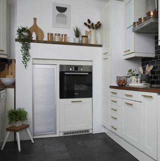 White cupboard kitchen with minimalistic décor and black mosaic tiles