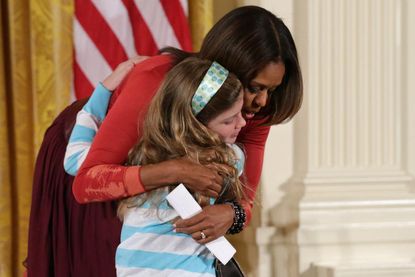 Girl hands Michelle Obama her unemployed father's resume