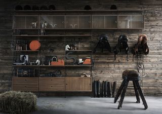 String shelves making a tack room from Skandium, in a garage with a chic wooden wall