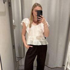 Woman in dressing room wears black top and black trousers