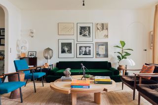 a living room with a green velvet sofa and gallery wall