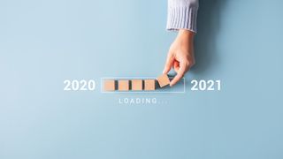 A hand placing wooden blocks symbolising a loading bar from 2020 to 2021
