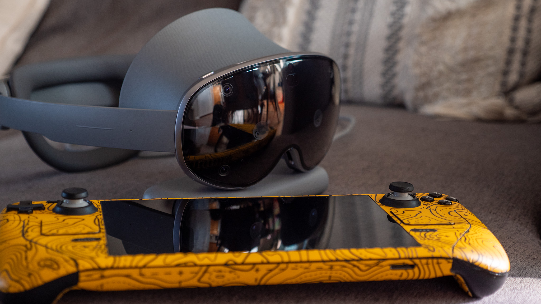 A Samsung Galaxy XR next to a Steam Deck wearing a yellow Dbrand skin