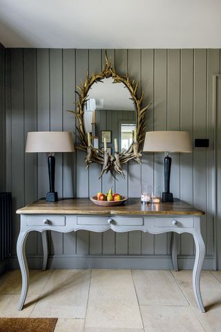 entrance hall with grey tongue and groove walls and console table with matching lamps and antler mirror