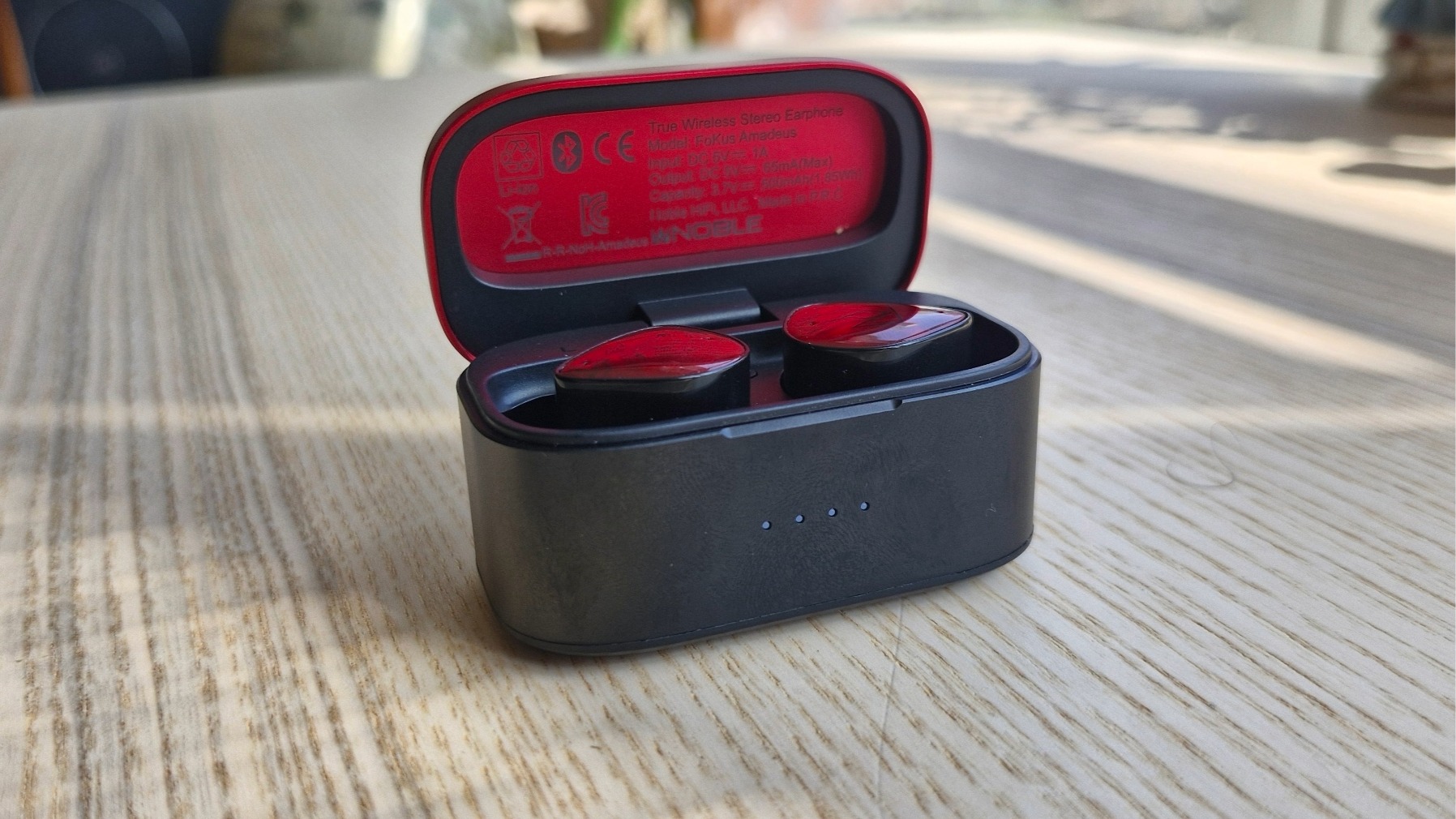 Noble FoKus Amadeus in-ear headphones, inside their carry case, on a wooden surface