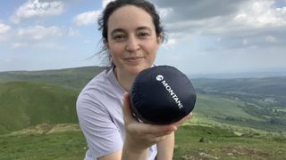 Julia Clarke holding the Montane Alpine 850 Nano Hoodie in its stuff sack