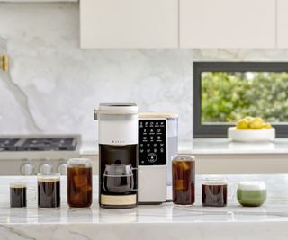 Bruvi coffee maker with cups of coffee and match on countertop