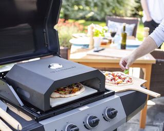 A pizza oven which sites on top of a gas bbq grill