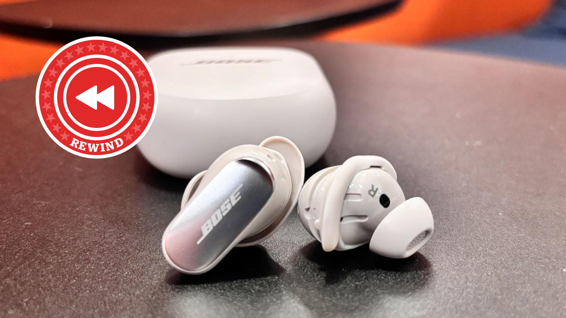 Bose earbuds on table with red lighting and rewind logo