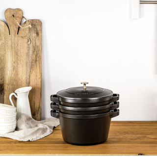 black stackable pot on a wooden worksurface with a mini white jug and chopping board