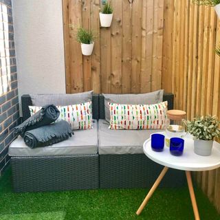 Airbnb courtyard area with fencing, small sofa and artificial grass